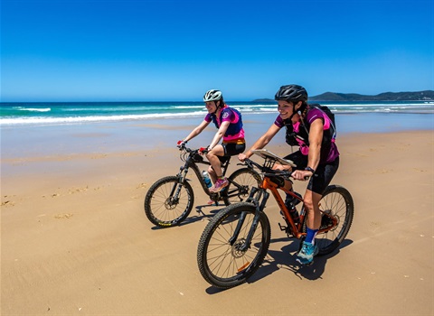 Women riding bicycles at the beach
